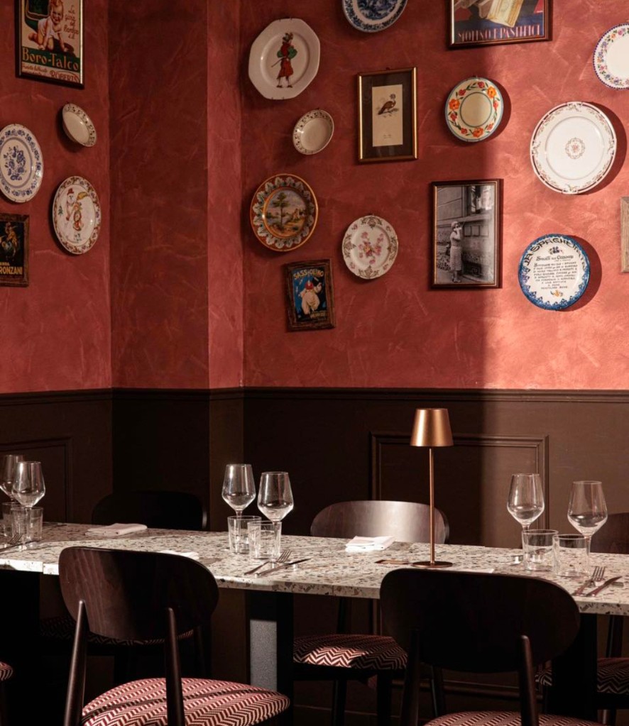 Sala della trattoria con parete terracotta e piatti decorati